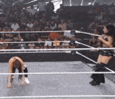 a woman is kneeling down in a wrestling ring with a wwe logo on the ring