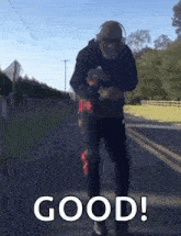 a man wearing headphones and sunglasses is walking down a road with the words good written on the bottom