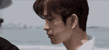 a close up of a man 's face while standing on a beach .