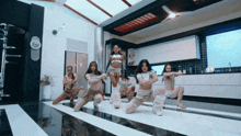 a group of women are dancing in a kitchen and one of them is wearing a crop top that says ' i am '