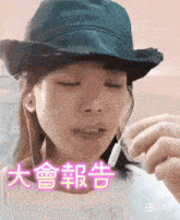 a woman wearing a hat and ear buds has chinese writing above her face