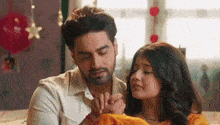 a man and a woman are holding hands and looking at each other while sitting on a bed .