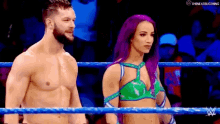 a man and a woman are standing in a wrestling ring and the man is shirtless