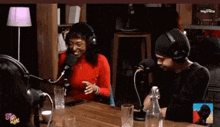 a man and a woman are sitting at a table with microphones .