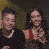 two women are sitting next to each other on a couch and one is laughing .