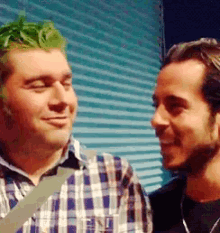 a man with green hair is standing next to another man in a plaid shirt