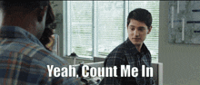 a man in a plaid shirt is talking to another man and says yeah count me in