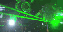 a group of people are dancing in a dark room with green lasers coming out of the ceiling