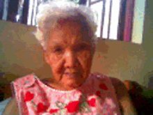 an elderly woman is wearing a pink dress with red roses on it