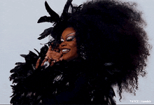 a woman in a black feathered outfit is smiling and has the tumblr logo on the bottom