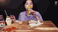 a woman is drinking a can of fanta