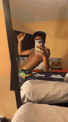 a shirtless man is taking a picture of himself in a mirror with his phone