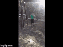 a man in a green shirt is swinging on a swing set