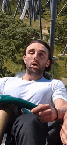 a man is riding a roller coaster at a theme park and making a funny face .
