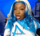 a woman with blue hair is wearing a shirt with the letter a on the front