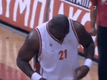 a basketball player wearing a number 21 jersey is standing on a court .