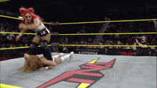 a woman is wrestling in a ring with a tna logo on the floor