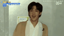 a young man wearing glasses and a white shirt is standing in front of a sign that says kshow123 on it
