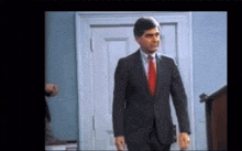 a man in a suit and red tie is standing in a doorway