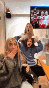a group of girls are sitting in front of a large screen with a picture of a soccer team on it