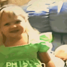 a little girl is wearing a green shirt that says phillips