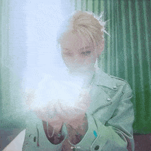 a woman in a green jacket is holding something in her hands .