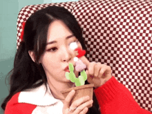 a girl in a red sweater is holding a stuffed cactus
