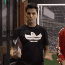 a man wearing a black adidas shirt with a ghost face on it
