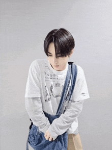 a young man wearing a white t-shirt and a denim messenger bag