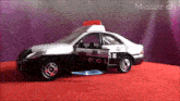 a black and white police car with the door open on a red carpet
