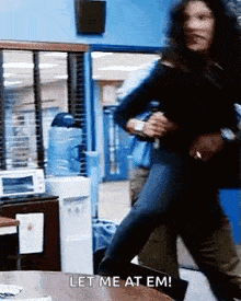 a woman is running in a room with the words let me at em written on the table .
