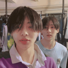 two boys are standing next to each other and one has a purple shirt on