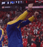 a man in a blue and yellow shirt stands in front of a toyota ad