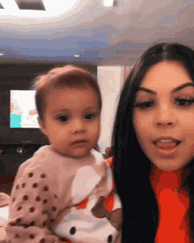 a woman is holding a baby in her arms in front of a television
