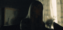 a woman is sitting on a couch in a dark room .