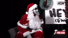 a man dressed as santa claus is sitting in front of a sign that says " hey crew "