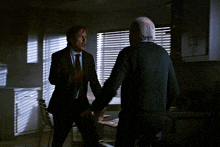 two men in suits and ties are fighting in a dark room