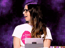 a woman wearing glasses and a t-shirt that says " kind to anyone "
