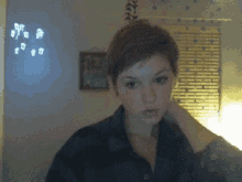 a woman with short hair is standing in front of a wall with a picture on it
