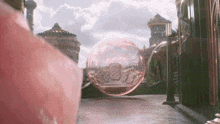 a large pink bubble is in the middle of a city