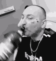 a man with a tattoo on his face drinks from a can