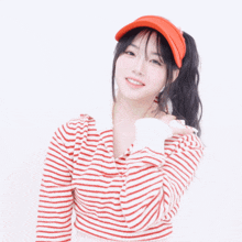a woman wearing an orange visor and a striped sweater covering her face