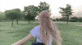 a woman with blonde hair is walking through a park .