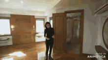a woman stands in an empty room with the words made in animatica on the bottom right