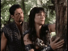 a man and a woman are standing next to each other in a forest