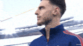 a man with a beard is wearing a blue and red adidas tracksuit
