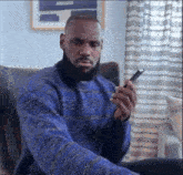 a man in a blue sweater is looking at his phone