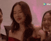 a woman in a red dress is smiling in front of a pink background with a play button that says wetv