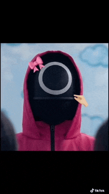 a person wearing a squid game mask with a pink bow on it
