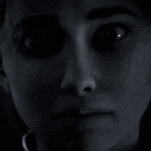 a close up of a woman 's face in the dark with her eyes glowing